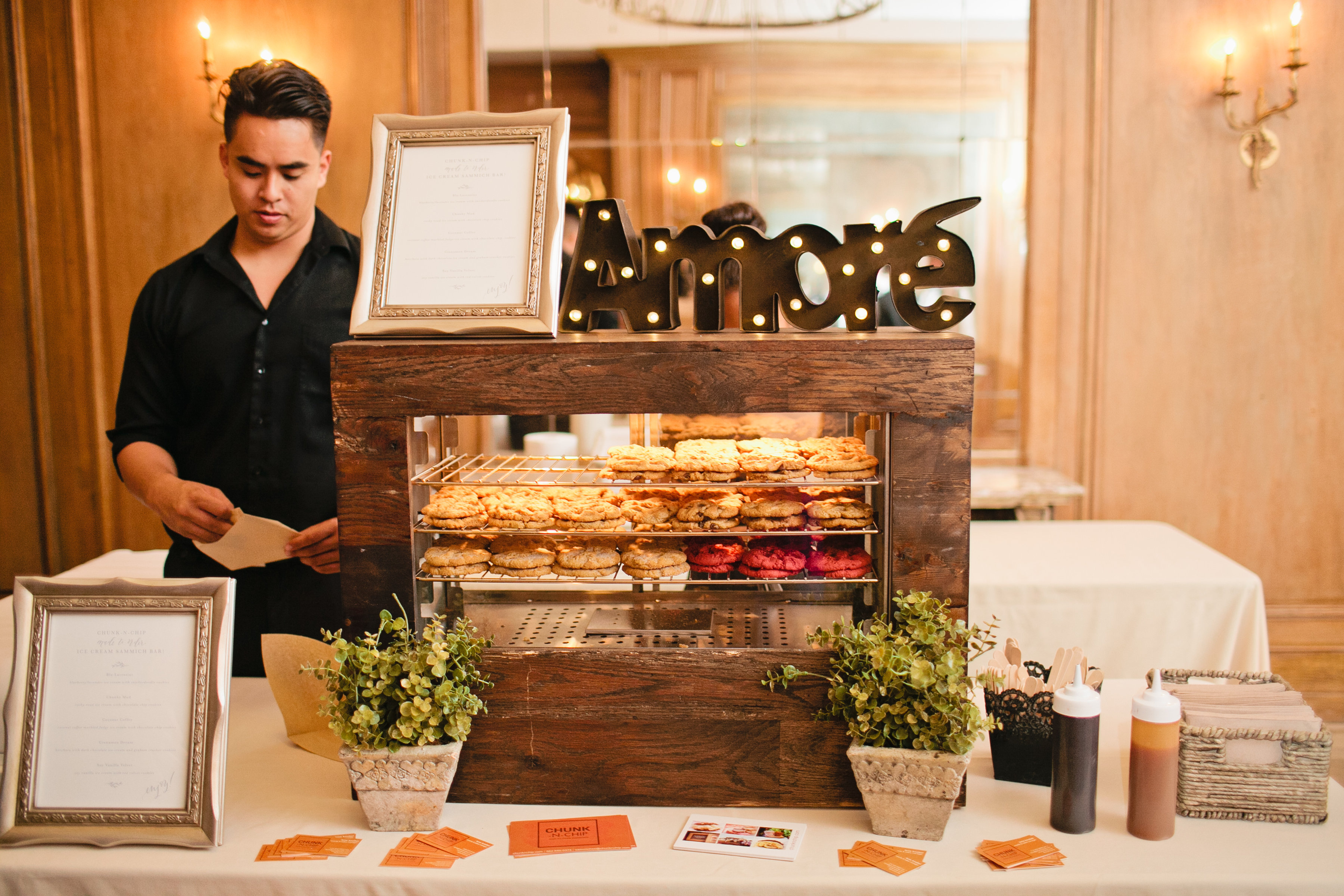 Chunk-N-Chip attendant serving warm cookies from a display case at a wedding reception